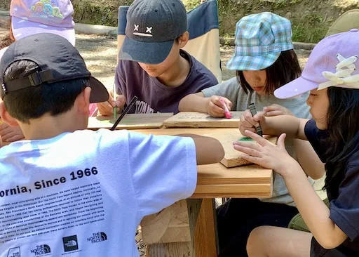 自然素材を使ったものづくりワークショップ, 子どもが自分の手で作るクラフト体験, 思い出を形にするキッズキャンプの創作活動, 集中して作品づくりに取り組む子どもたち